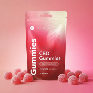 Hemnia Sour Strawberry CBD Gummies pouch with sugar-coated gummies on a pink background.