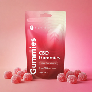 Hemnia Sour Strawberry CBD Gummies pouch with sugar-coated gummies on a pink background.